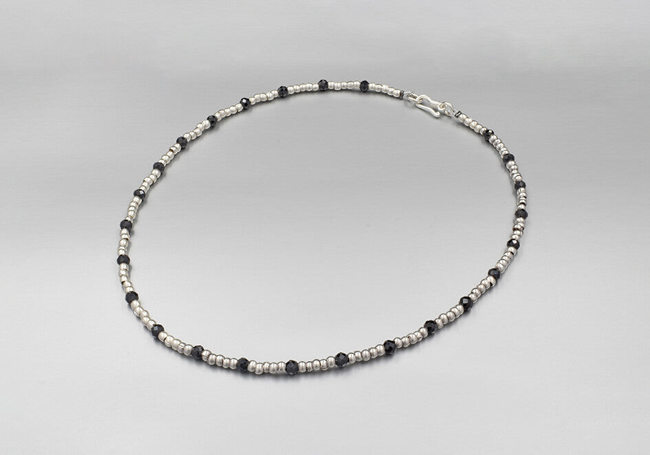 Colour splash beaded necklace with silver beads and black spinel beads over a play grey background
