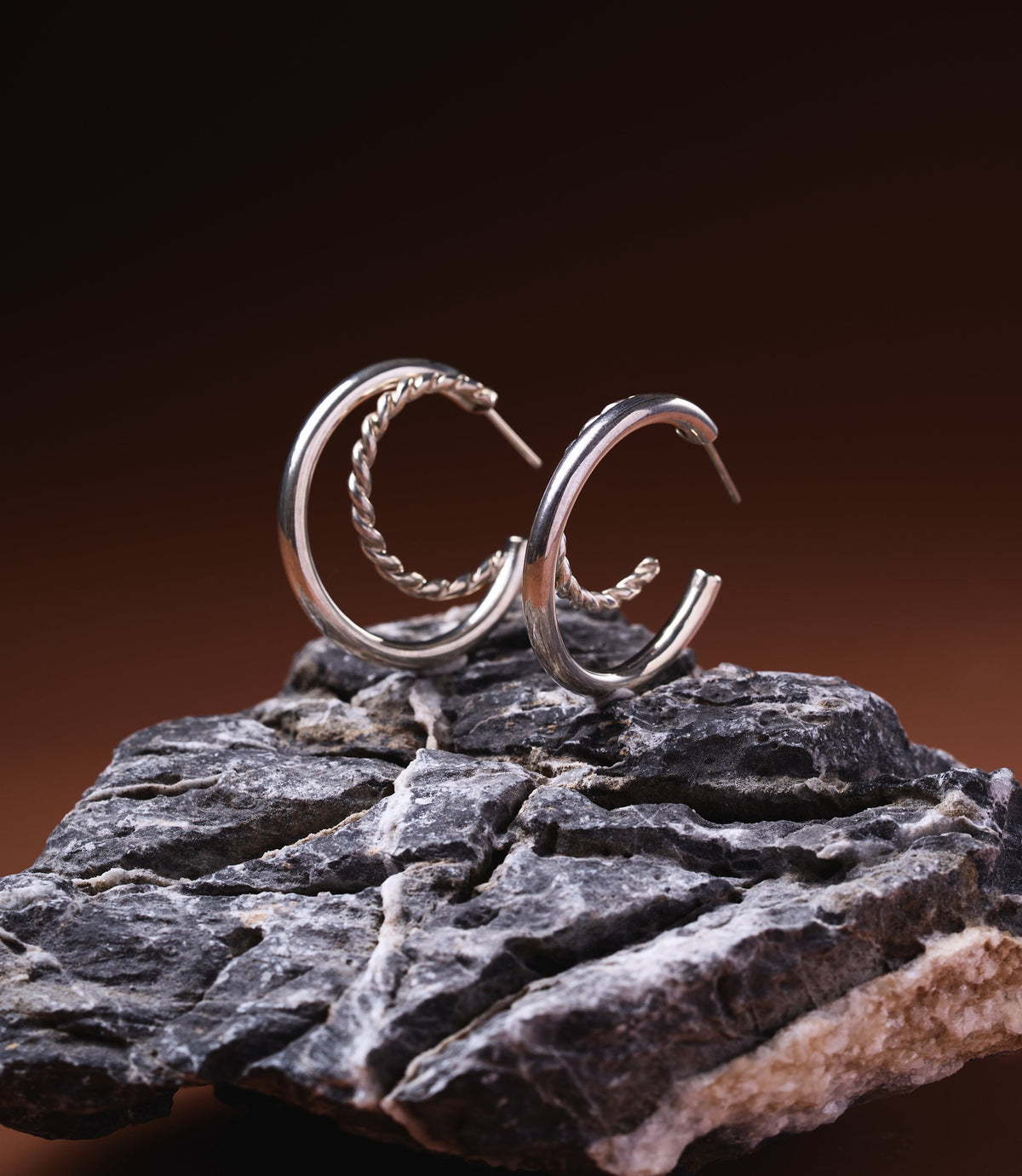 Dahlia Double Hoop Earrings in sterling silver 925 with polished and twisted rope band design, displayed on dark rock