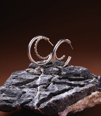 Dahlia Double Hoop Earrings in sterling silver 925 with polished and twisted rope band design, displayed on dark rock