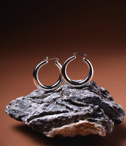 Daphne Sterling Silver Hoops — polished 925 sterling silver tubular hoop earrings displayed on natural stone