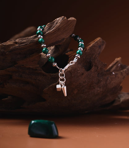 Gaia Malachite Bracelet with pure silver beads and charm pendant on rustic wood background