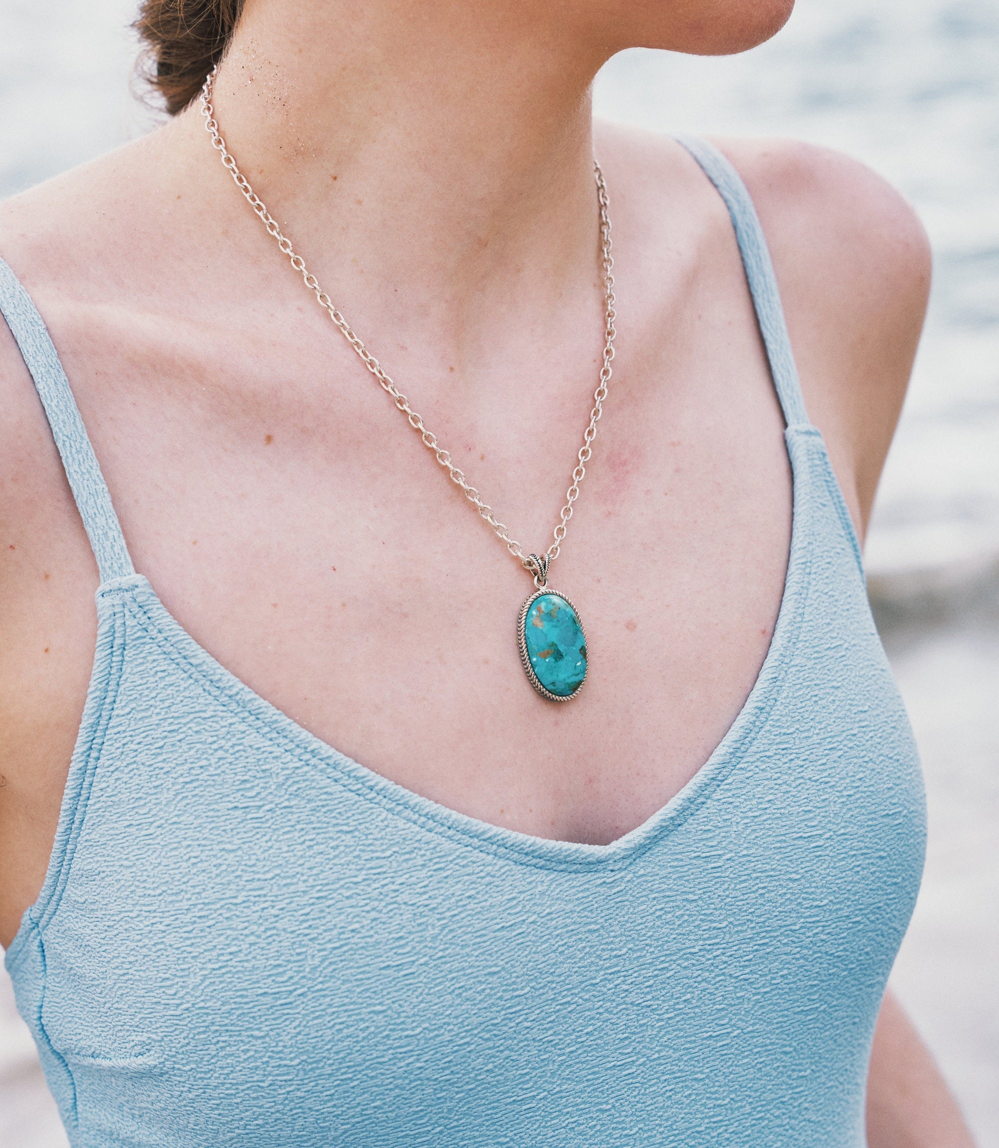 Model wearing the Aurea Necklace, a pure silver necklace with a striking synthetic turquoise pendant.