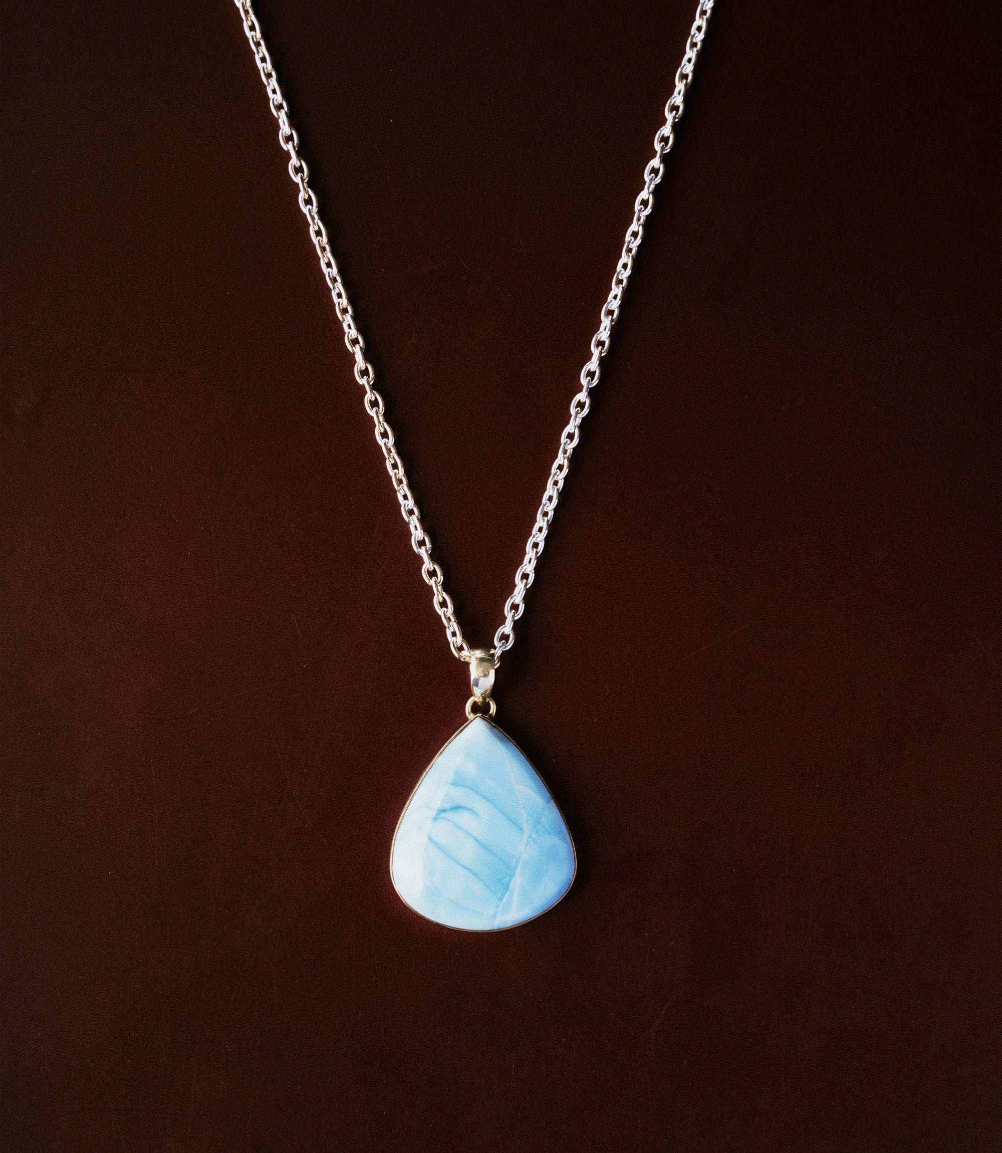 The Aurelia Necklace in 925 Sterling silver features a smooth sky-blue stone pendant with delicate marbled details.