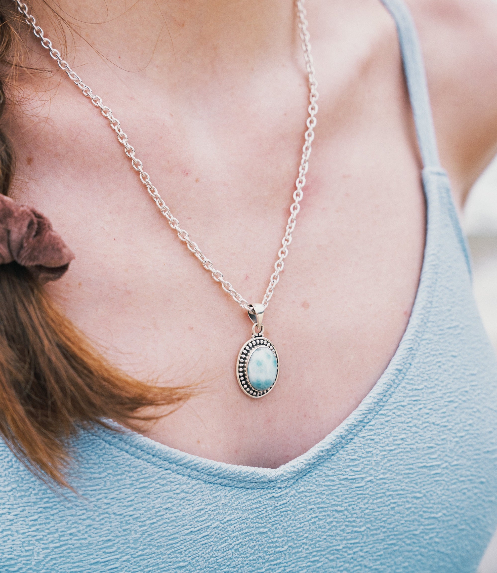 Model wearing the Celia Necklace, a minimalist 925 sterling silver necklace with an oval synthetic larimar pendant.