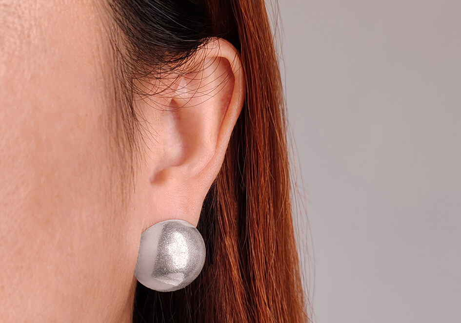 A model wearing a pair of handmade Audrey Dome shape stud earrings from Hill to Street Silver jewelry.