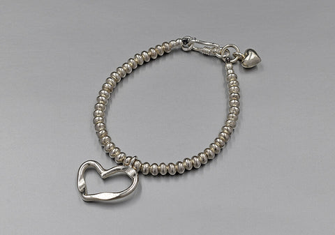 A cherished heart beaded bracelet with cut-out heart charm on light grey background.
