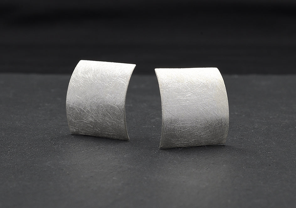 Pair of curved square stud earrings from Hill to Street over black background