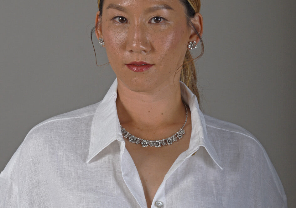 Model wearing a pair of fleur silver stud earrings combined with a silver necklace with butterfly and flower silver charms from Hill to Street