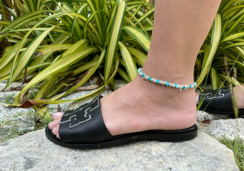 Zoomed-in photo of a model wearing irregular beads stackable beach anklet from Hill to Street with black open-toe shoes