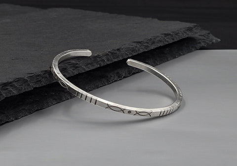 Lines square silver bangle from Hill to Street seating over a dark stone background