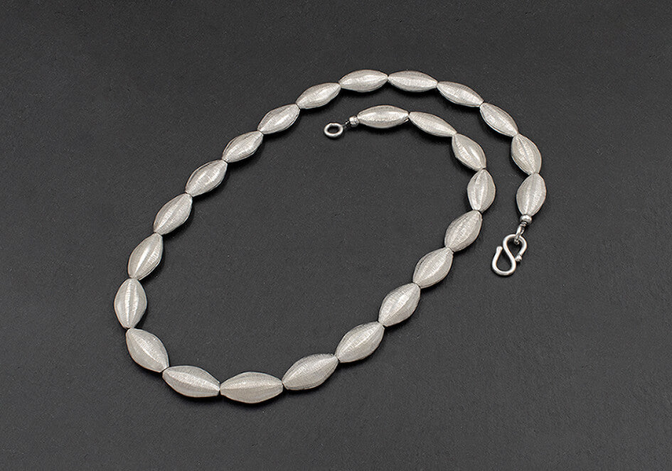 Photo of a long oval silver beads necklace over a black background