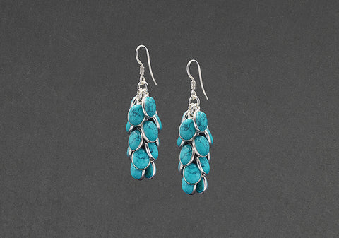 Pair of Luna dangling turquoise earrings from Hill to Street over black background