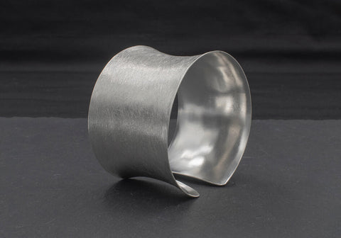 Matte-finished medium silver cuff bracelet over black background with stone