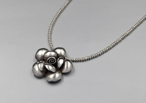 Medium size pure silver rose mawar flower pendant with beaded pure silver necklace on light grey background.