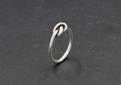 Minimalist knot ring from Hill to Street over black background