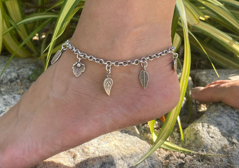 Zoomed-in photo of a model wearing a multi-charm silver chain anklet from Hill to Street barefoot