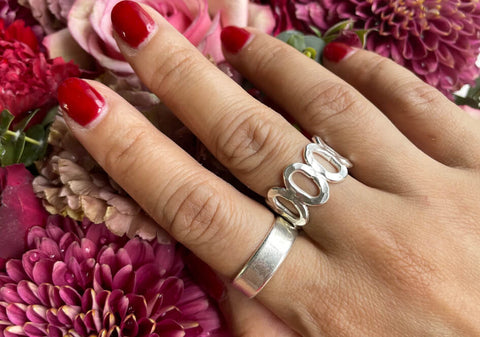 Model wearing a multi-circle adjustable silver ring from Hill to Street over flower background