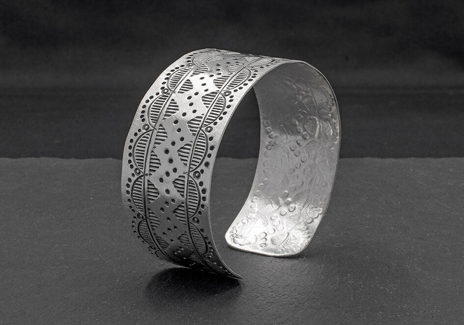 Patterned flat cuff bangle from Hill to Street over dark grey background