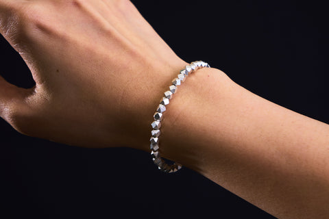 Lumin Bracelet worn on the wrist, stacked for a high-shine statement look