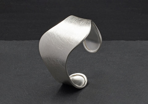 Close-up of the Lydia Bangle showing the matte wave detail and brushed pure silver finish.