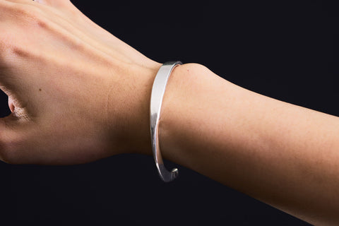 Model wearing Rhea Bangle, a minimalist pure silver bracelet for everyday styling.