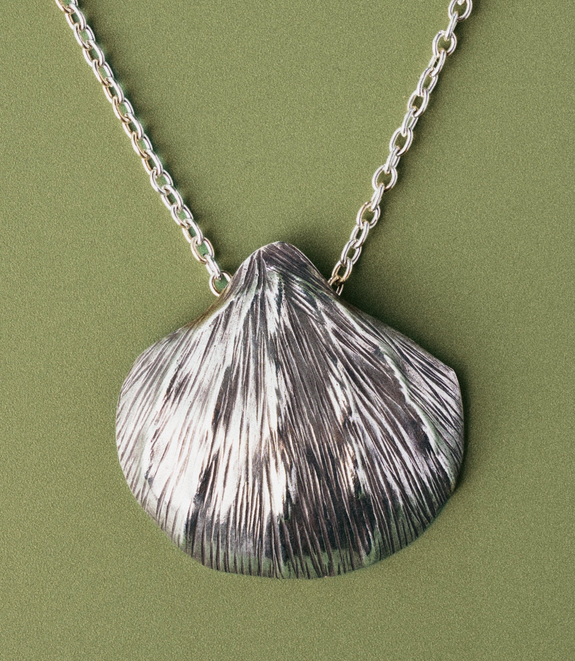 Close-up of the Tala Necklace shell pendant showing hand-etched fine line texture mimicking a real seashell surface
