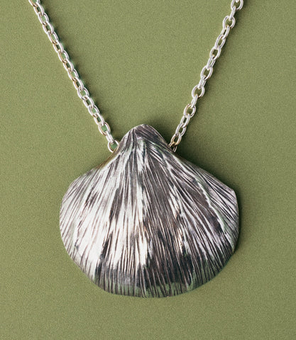 Close-up of the Tala Necklace shell pendant showing hand-etched fine line texture mimicking a real seashell surface