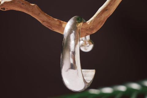 Close-up of the Apsara Bangle showing the sharp triangular tip and rounded end with polished pure silver finish.