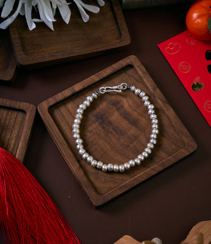 Anyi Bracelet in pure silver featuring large round silver beads, handcrafted bracelet laid flat on a clean surface