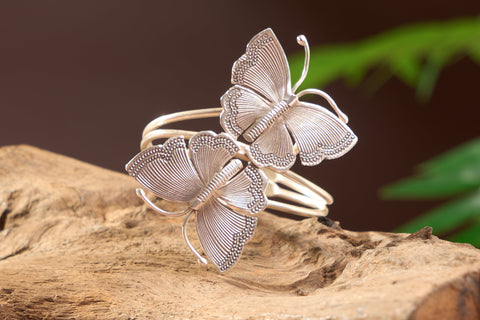 The Calista Butterfly Bangle in pure silver featuring two sculpted butterflies on an open cuff design.