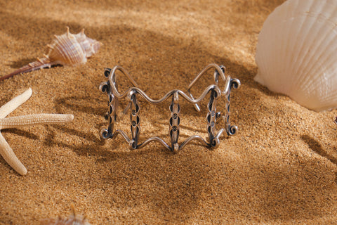 The Gael Bangle in pure silver featuring sculptural wave-inspired curves and silver droplet details.
