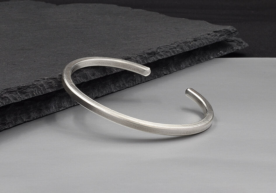 Close-up of the Lily Bangle's square wire edge in pure silver, showing clean angular craftsmanship