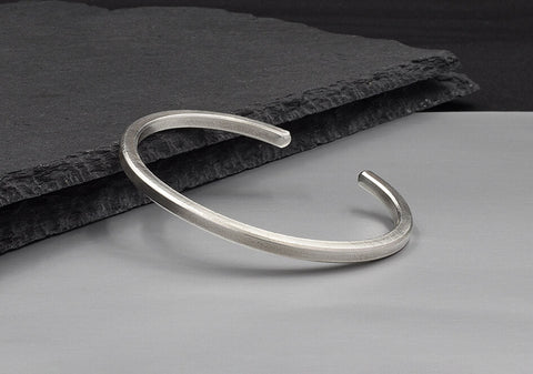 Close-up of the Lily Bangle's square wire edge in pure silver, showing clean angular craftsmanship