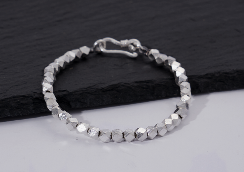 Close-up of Lumin Bracelet's faceted pure silver beads showing light-catching texture and craftsmanship detail