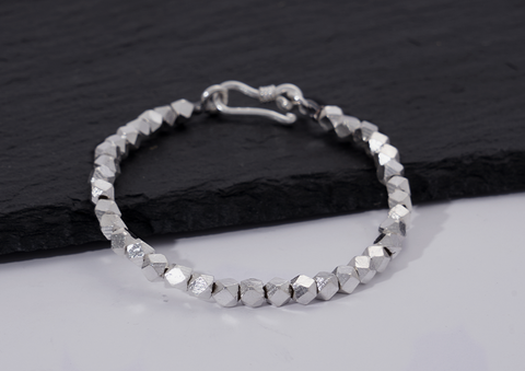 Close-up of Lumin Bracelet's faceted pure silver beads showing light-catching texture and craftsmanship detail