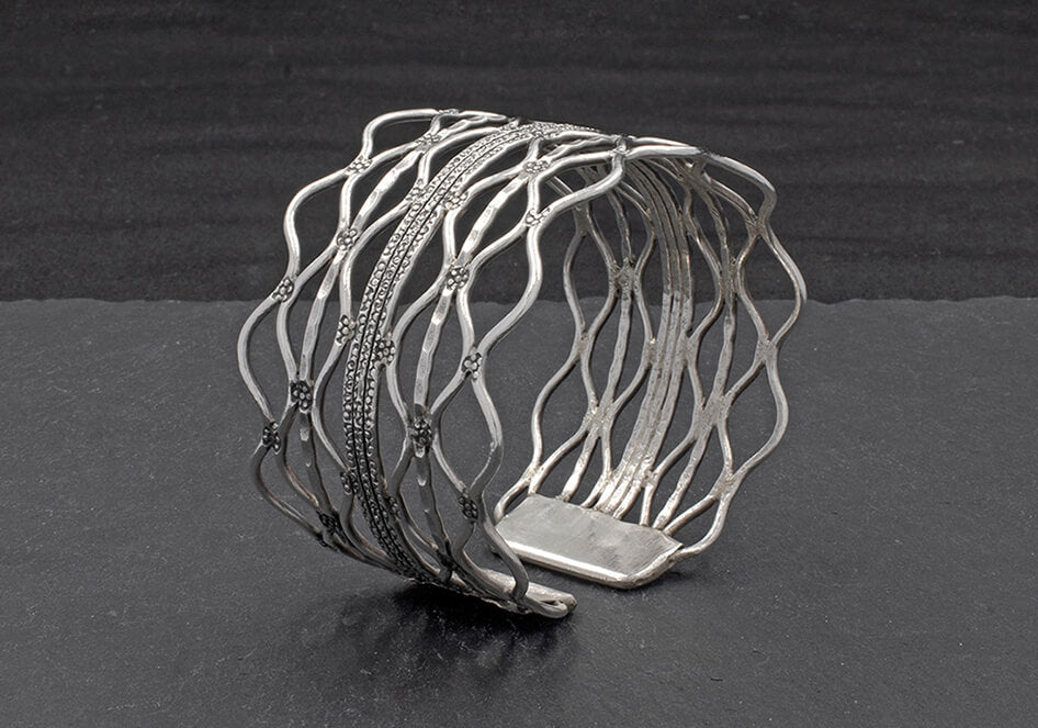 Close-up of hand-stamped texture and flowing wavy wire detail on the pure silver Nerina Bangle