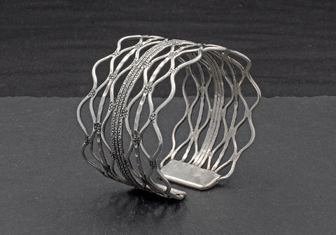 Close-up of hand-stamped texture and flowing wavy wire detail on the pure silver Nerina Bangle