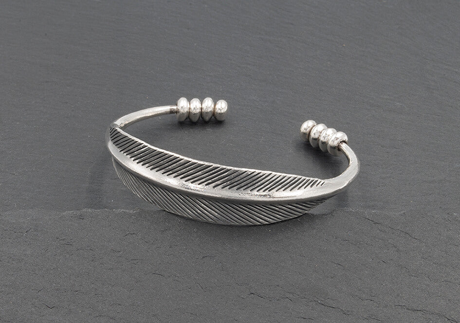The Sylvie Bangle in pure silver featuring sculpted flat leaf details and polished silver beads on an open cuff design.