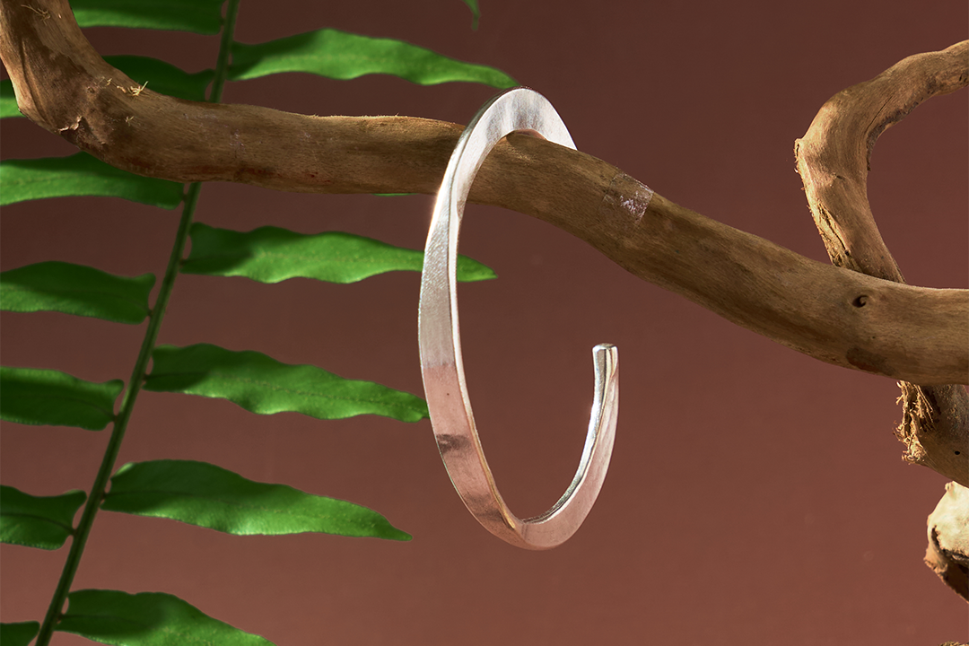 Close-up of Rhea Bangle showing reverse-flat edge detail and smooth pure silver finish.