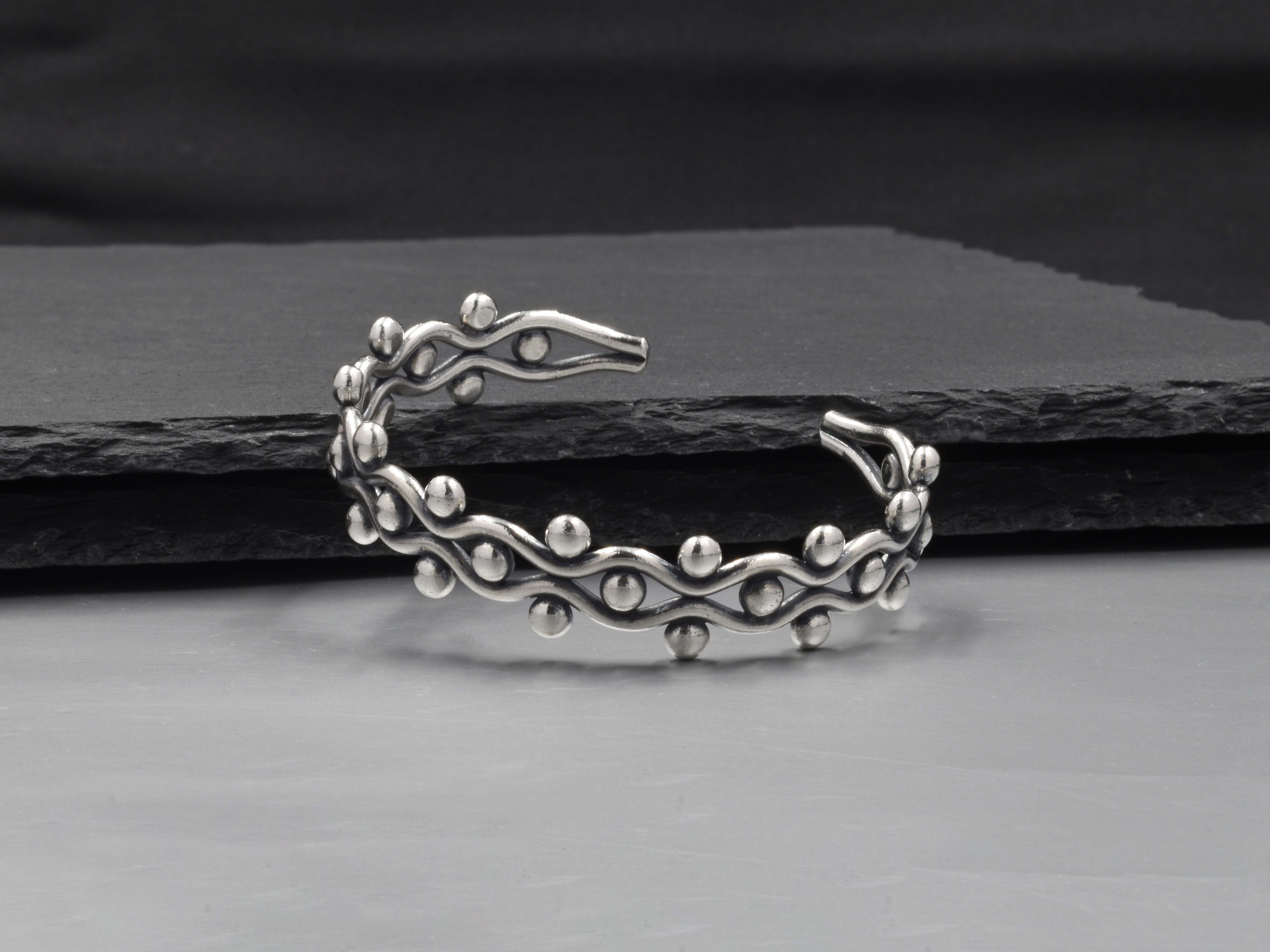 Close-up of Mariela Bangle showing fine dot-work, tribal motifs, and brushed pure silver finish.