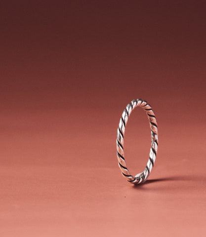 Alice Ring — handcrafted pure silver rope-twist band on a warm terracotta background