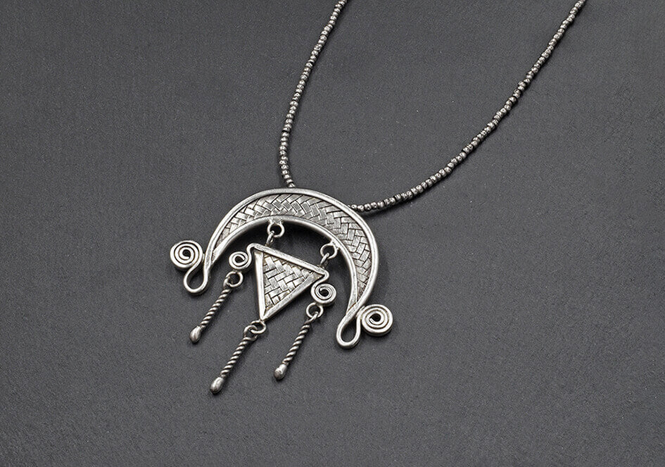 Anong Pure Silver Tribal Necklace with woven crescent pendant, triangle motif, spiral details, and twisted tassel drops on a ball chain