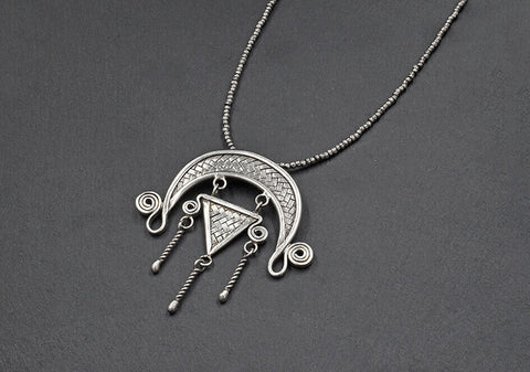 Anong Pure Silver Tribal Necklace with woven crescent pendant, triangle motif, spiral details, and twisted tassel drops on a ball chain