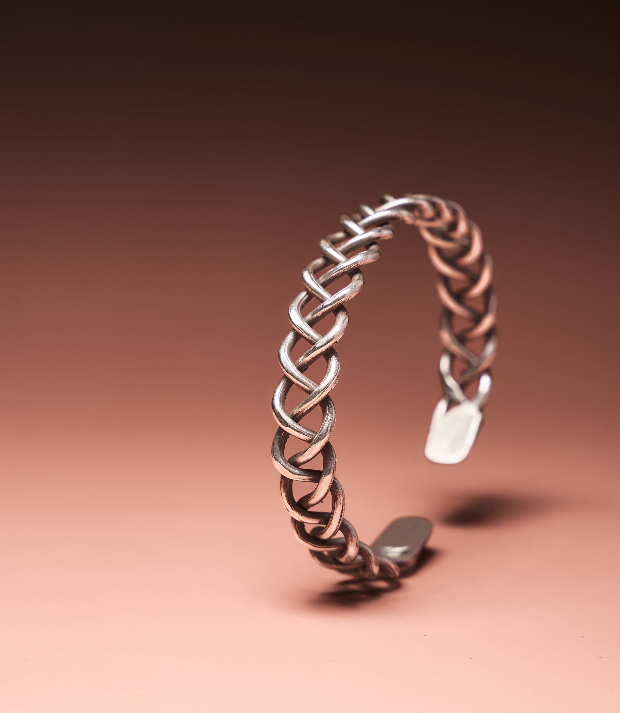 The Elowen Bangle in pure silver featuring an intricate woven design with a handcrafted braided finish.