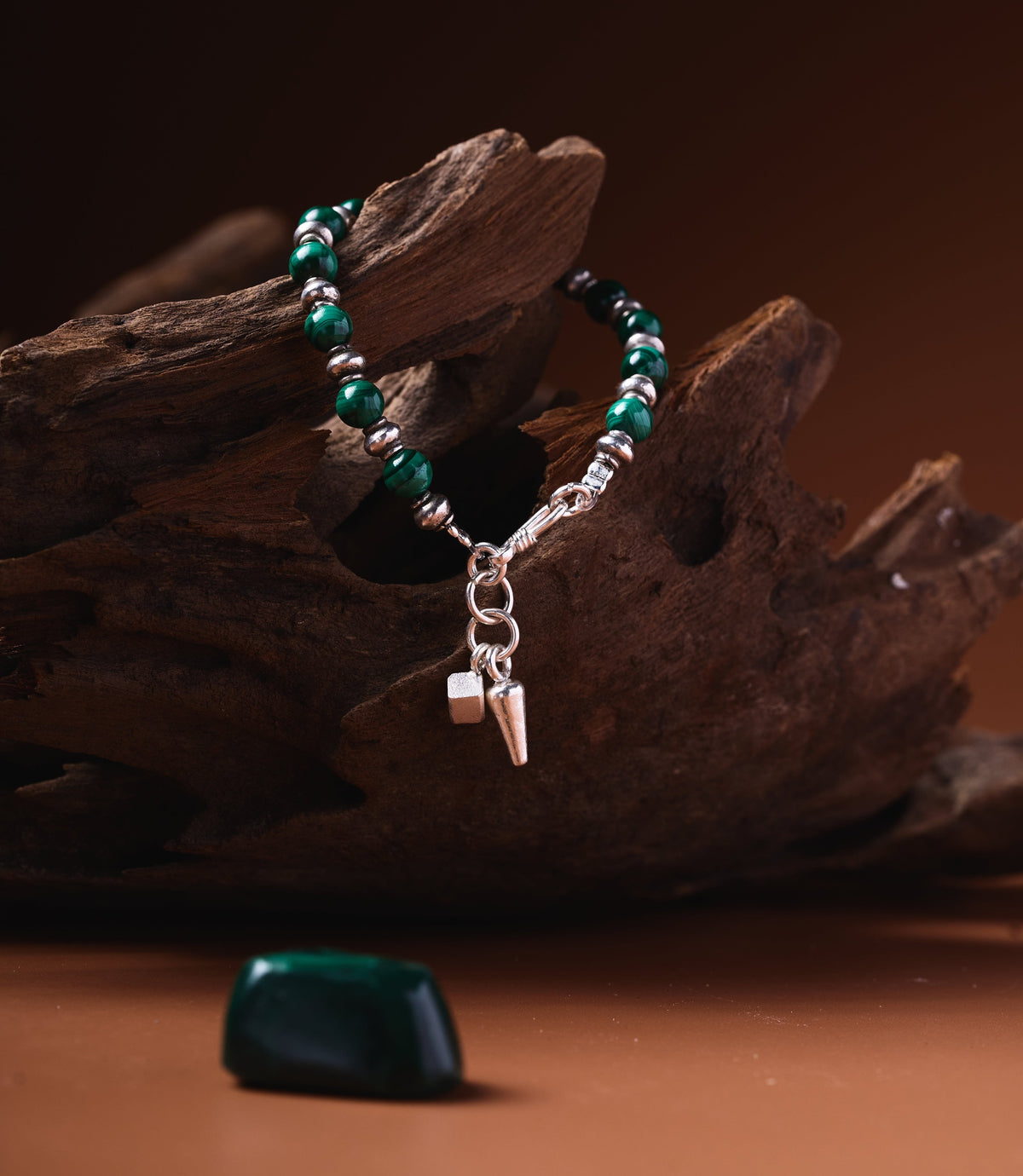Gaia Malachite Bracelet with pure silver beads and charm pendant on rustic wood background