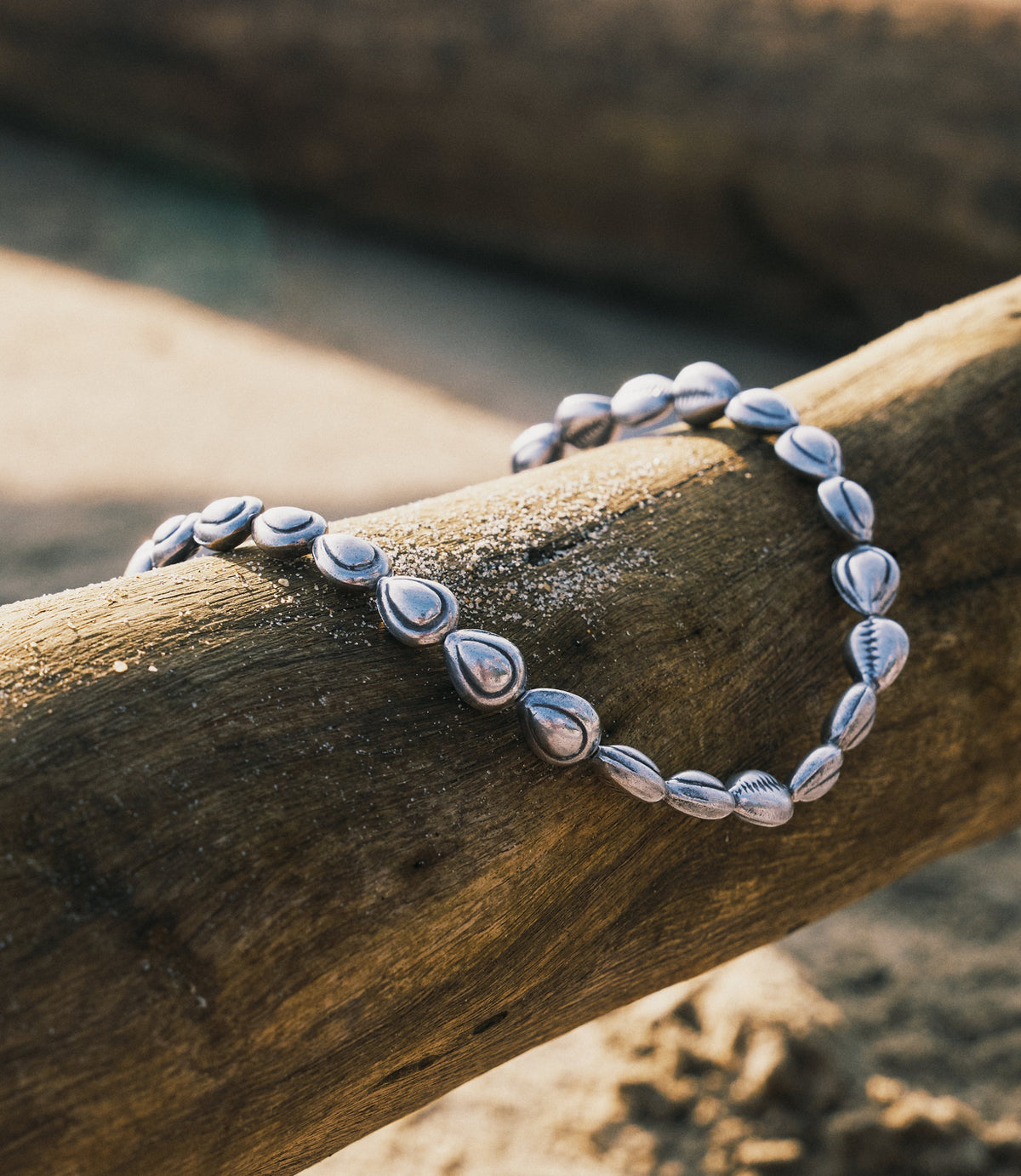 Harper Necklace in pure silver with shell beads strung on fish line, laid flat on a neutral surface