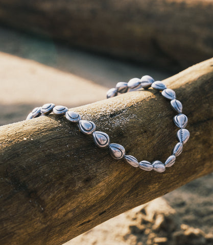 Harper Necklace in pure silver with shell beads strung on fish line, laid flat on a neutral surface