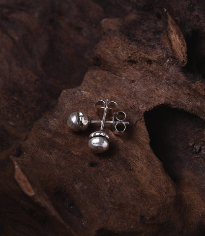 Minimalist pure silver flower bud studs worn as everyday earrings for a clean, elegant look