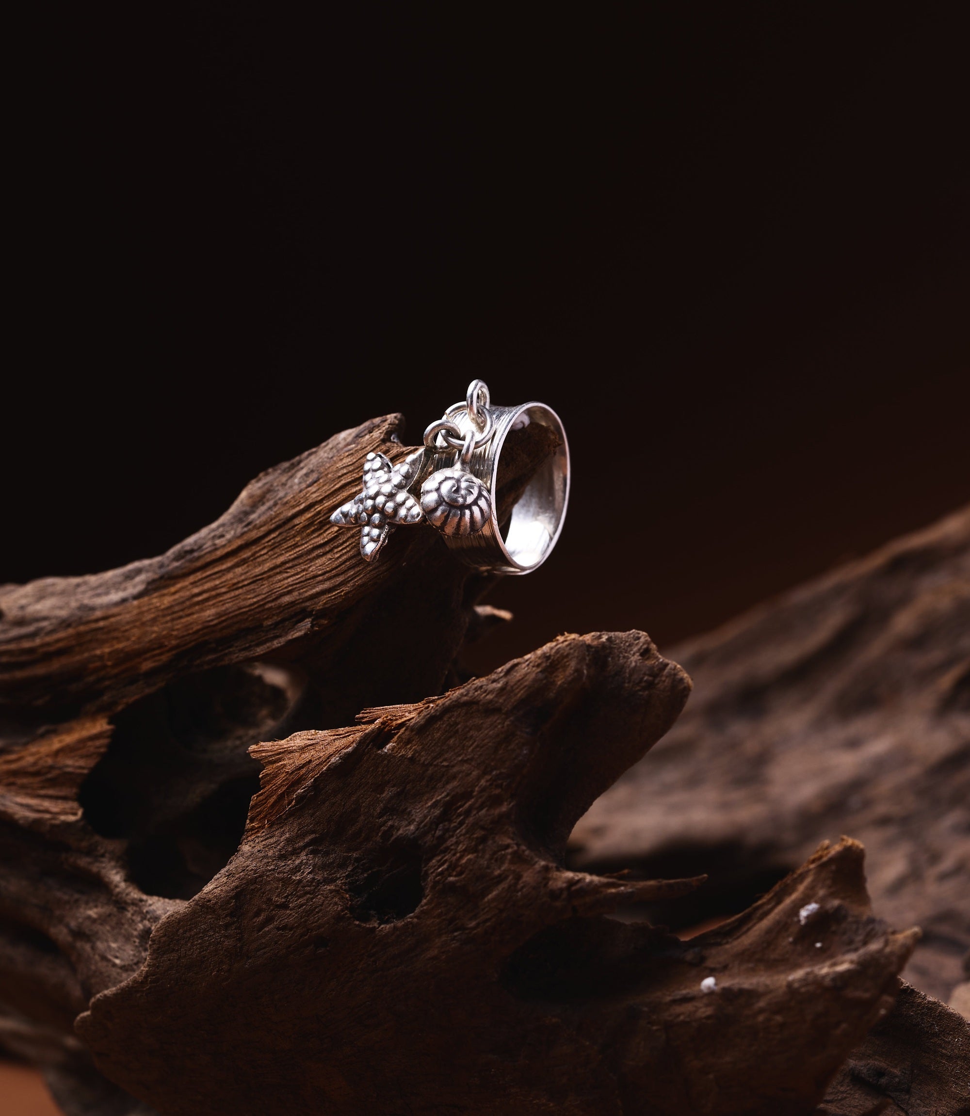Pure silver charm ring with starfish, shell, and pearl-inspired details on a layered band