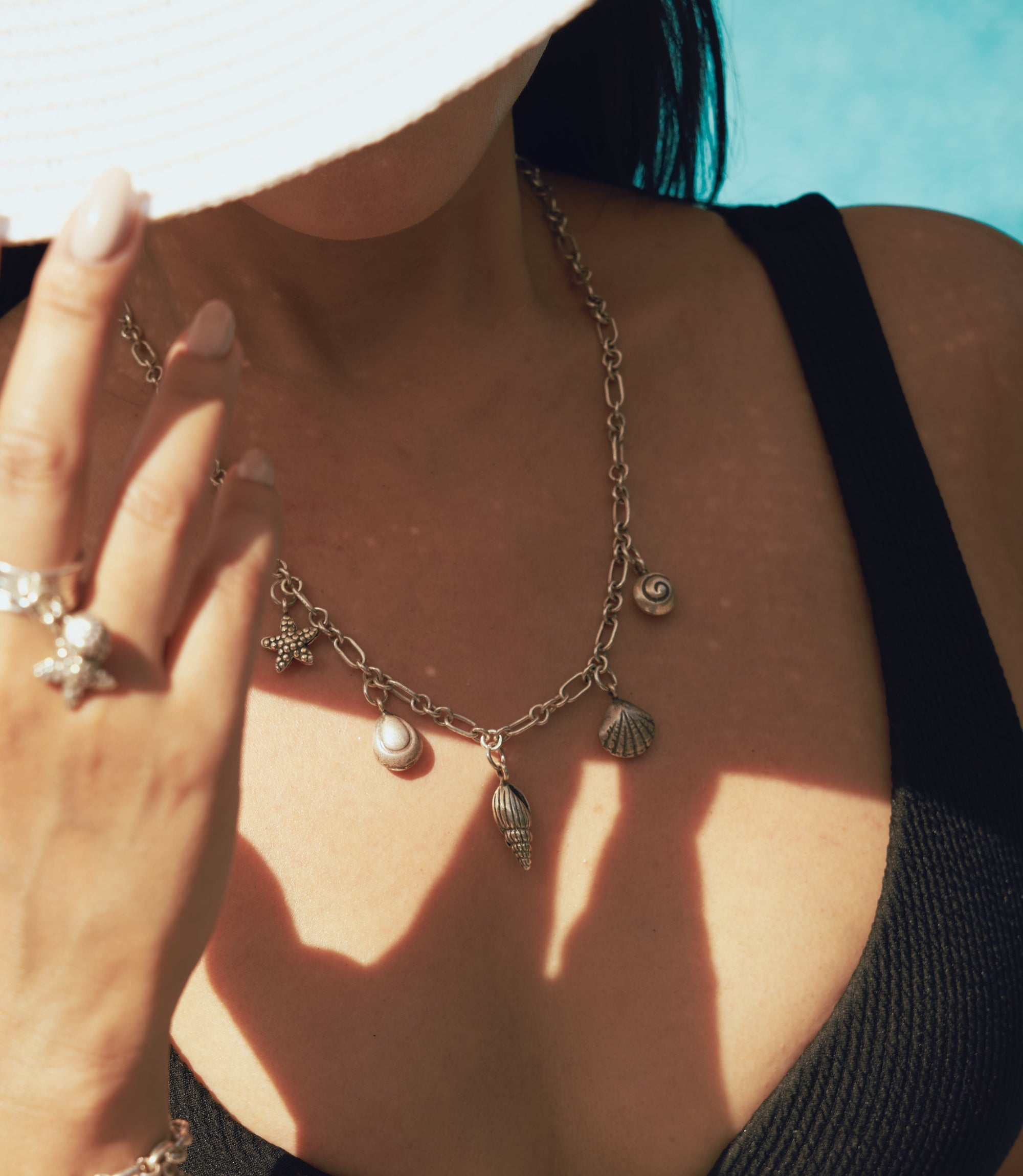 Model wearing the Sienna Necklace, a pure silver charm necklace inspired by coastal elements.